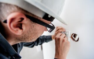 Man in a hardhat fixing a light switch.