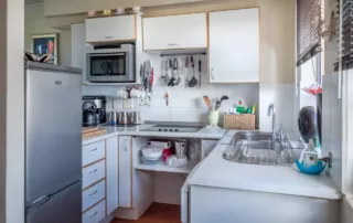 A photo of a small apartment building with a fridge and cooktop.