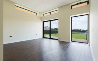 An empty apartment with white walls and wood floors.