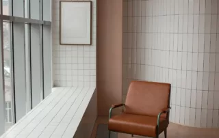 An empty apartment with a single chair and tiled backsplash.