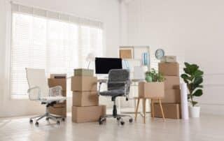 Moving day. Cardboard boxes, computer and furniture in office