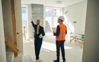 Female client and male engineer standing in room under construction